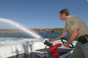Deputy operating Water hose on boat in harbor