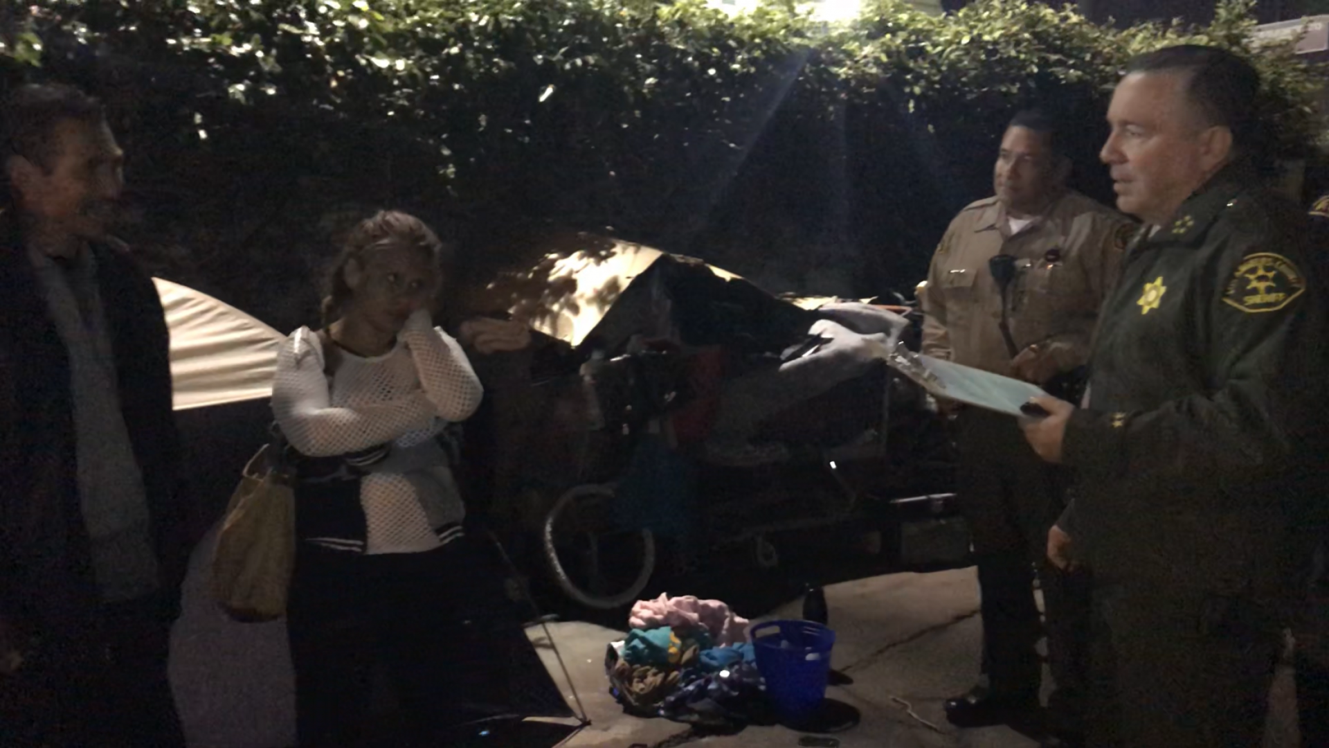 Sheriff Villanueva speaking to a man and woman in an alley