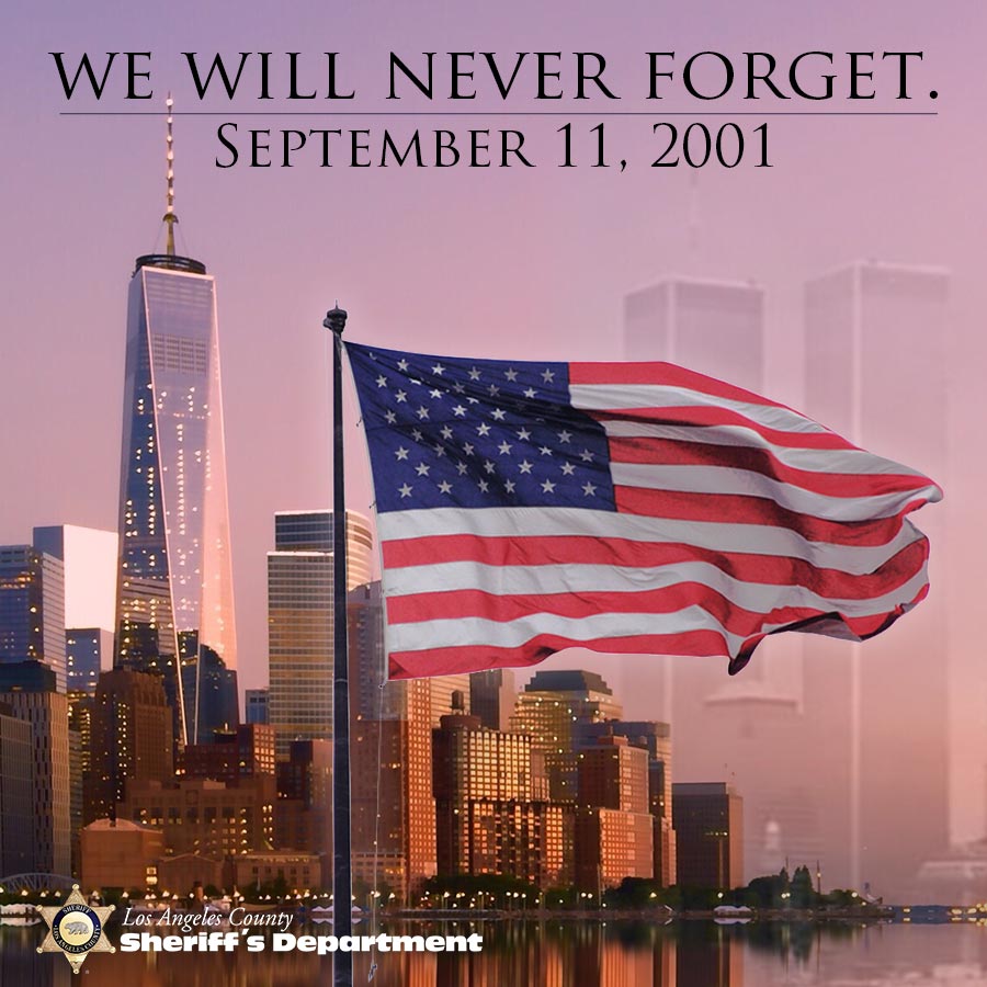 We Will Never Forget, September 11, 2001. Image of the american flag waving over the One Trade Center Tower on the left of flag and the Right side of flag are the Twin towers very faint over the orange purple sky.