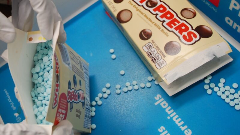 Box of candy open revealing small round pills. Instead of choclate candy that is depicted on the box.
