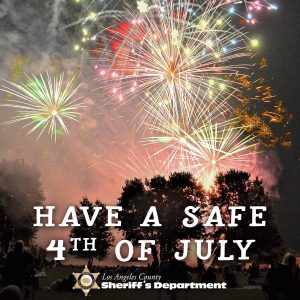 Image of fireworks in the night sky and trees off in the distance, People are sitting in lawn chairs watching a fire work show. Have a safe 4th of july. graphic of sheriff's gold star next to the words, Los Angeles County Sheriff's Department