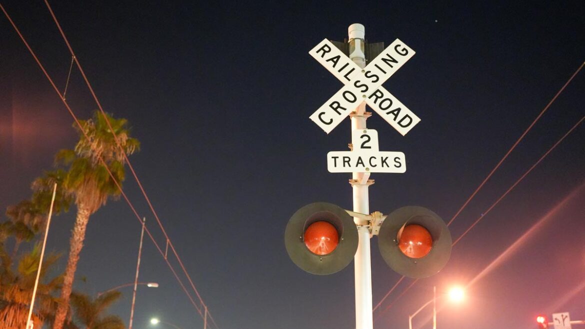 picture of a night sky, the Rail Road sign is centered near a rail road crossing.
