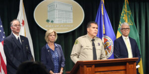 Sheriff Luna at a poduim with District Attorney Gascon, and Supervisor Janice Hanh in the background