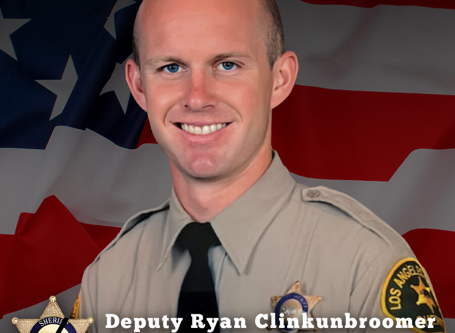 Image of Deputy Clinkunbroomer smiling. His portrait image is in front of a section of the american flag. He is wearing a tan longsleeve shirt with a black tie. There is a Sheriff badge over his left side. Words read: Deputy Ryan Clinkunbroomer, End of Watch 9-16-2023.