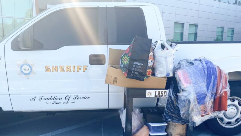 White truck parked with a cart of donations next to it. Sheriff logo is on the door.
